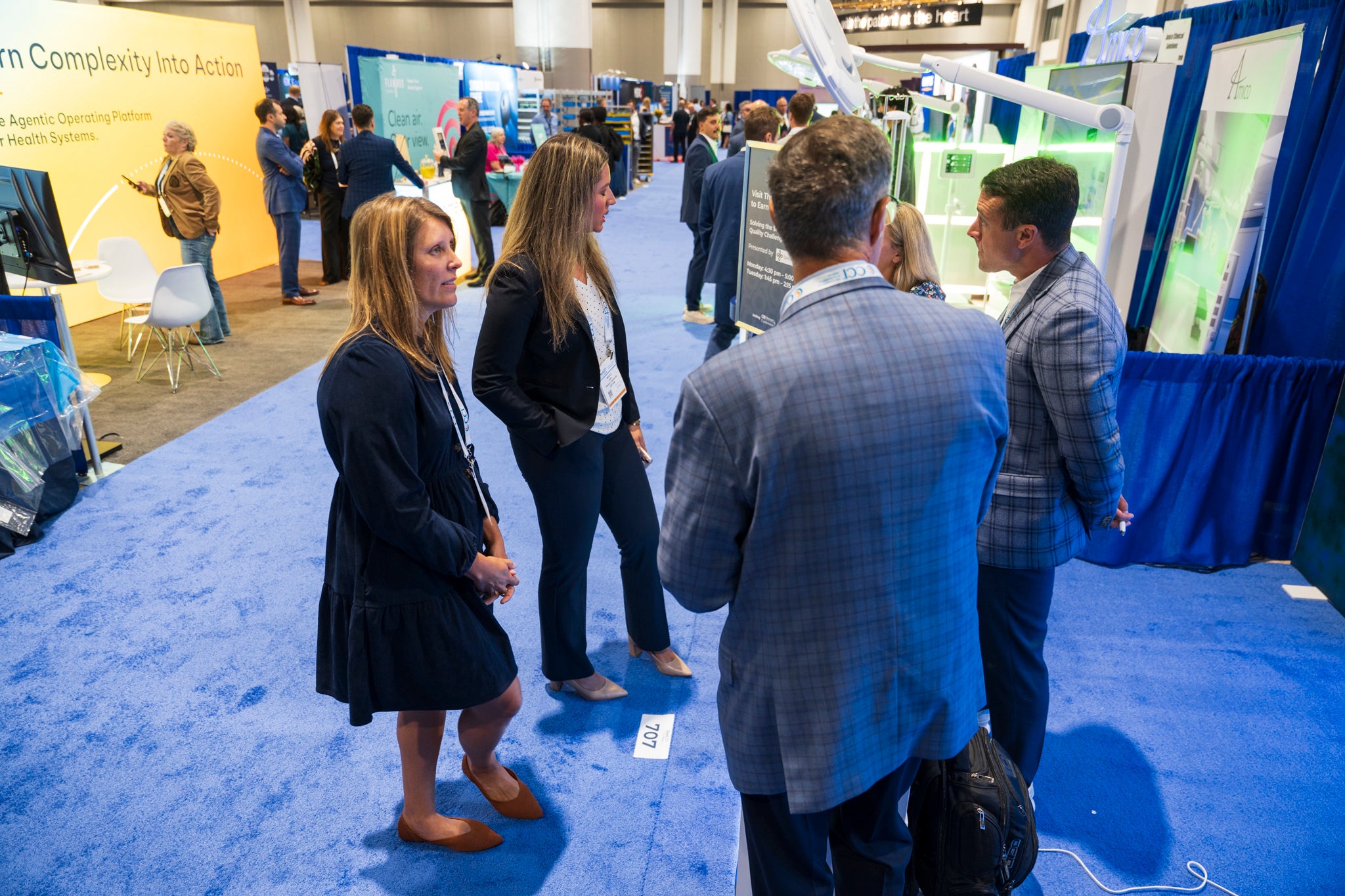 Attendees talking with exhibitors along a carpeted aisle